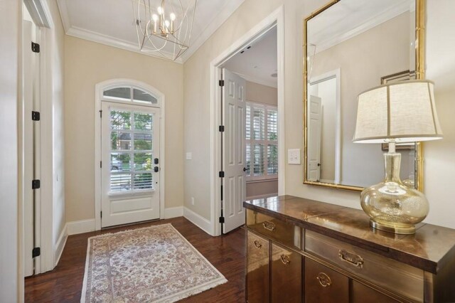 entryway featuring a notable chandelier, ornamental molding, and dark wood-type flooring