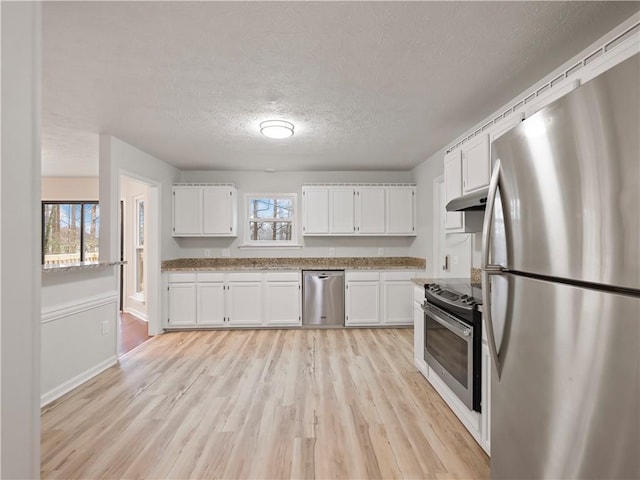 kitchen featuring white cabinetry, a textured ceiling, appliances with stainless steel finishes, a healthy amount of sunlight, and light hardwood / wood-style floors