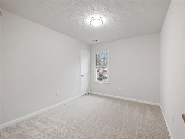 carpeted empty room with a textured ceiling