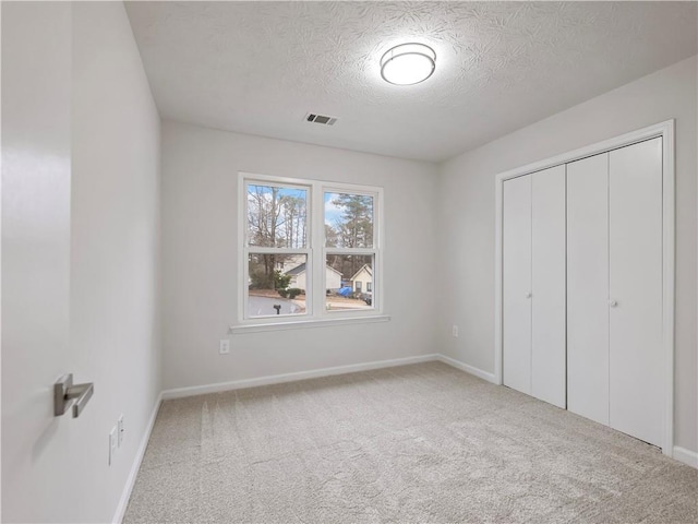 unfurnished bedroom with a closet, a textured ceiling, and carpet flooring