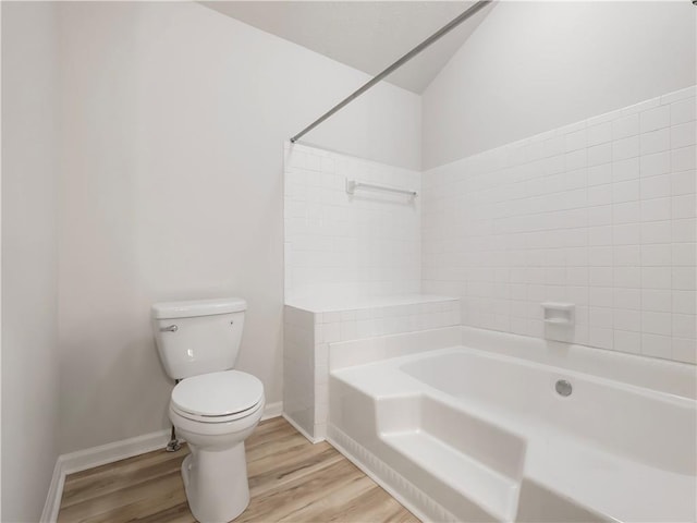 bathroom featuring wood-type flooring, plus walk in shower, and toilet