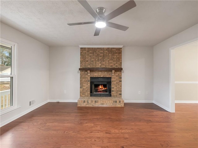 unfurnished living room with ceiling fan, a fireplace, dark hardwood / wood-style floors, and a textured ceiling