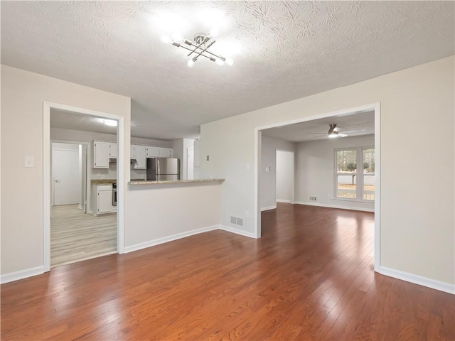 unfurnished living room with ceiling fan, wood-type flooring, and a textured ceiling