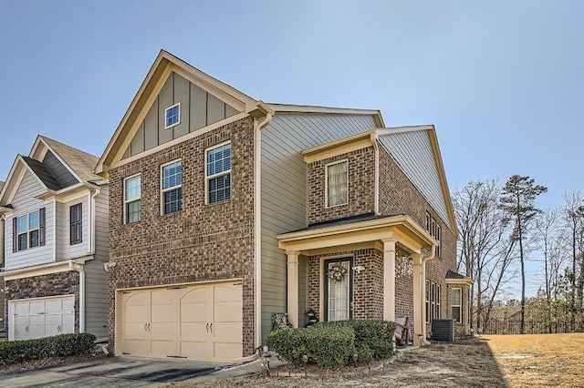 view of front of property featuring central air condition unit, driveway, board and batten siding, an attached garage, and brick siding