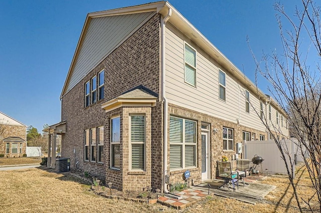 back of property featuring brick siding, central AC, a patio, and fence