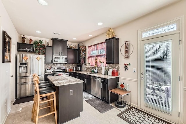 kitchen with visible vents, a sink, a center island, appliances with stainless steel finishes, and decorative backsplash