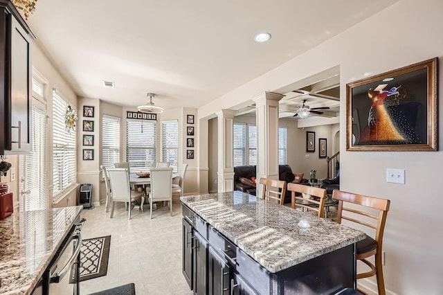 kitchen with light stone countertops, visible vents, coffered ceiling, ornate columns, and baseboards