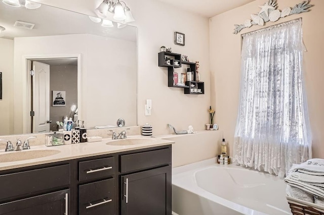 bathroom with a bath, visible vents, double vanity, and a sink