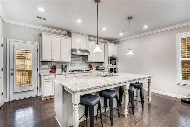 4831 Miller Hill Rd, Buford, GA 30518 - kitchen with under cabinet range hood, a sink, baseboards, a breakfast bar area, and dark wood-style flooring