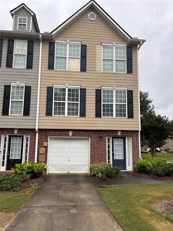 6231 Redan Overlook, Lithonia, GA 30058 - townhome / multi-family property with asphalt driveway, brick siding, an attached garage, and a front yard