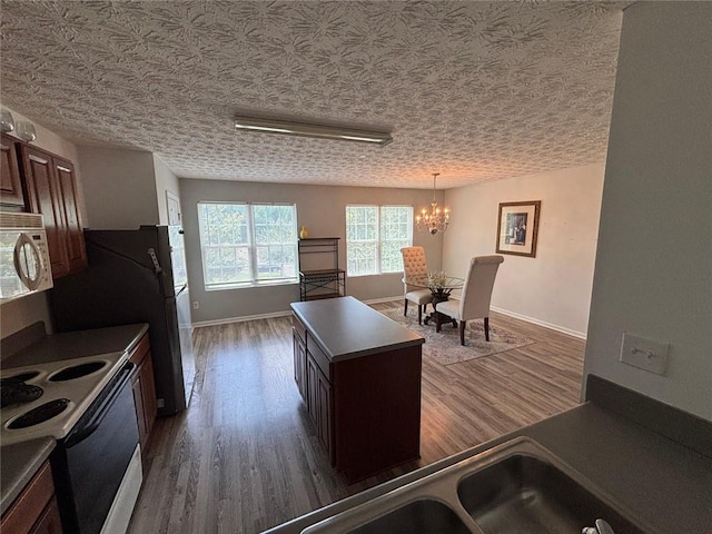 6231 Redan Overlook, Lithonia, GA 30058 - kitchen featuring white microwave, range with electric cooktop, a chandelier, wood finished floors, and a center island