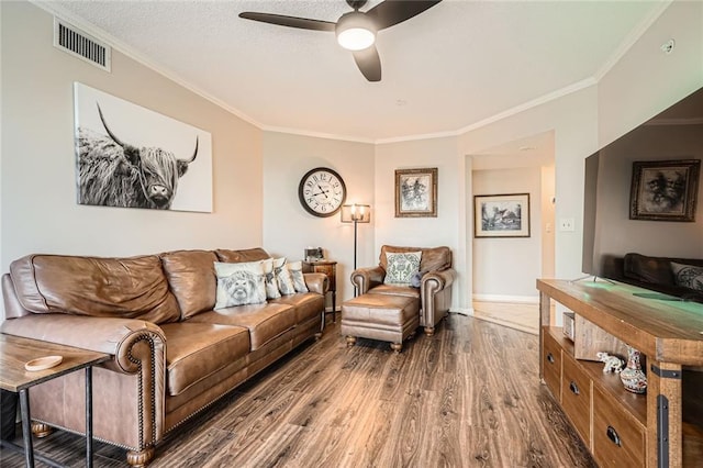 living room with ceiling fan, visible vents, ornamental molding, and wood finished floors