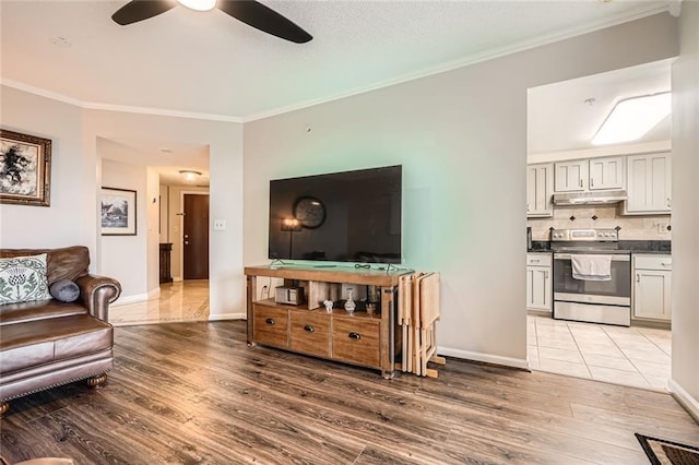living room with crown molding, baseboards, ceiling fan, and wood finished floors