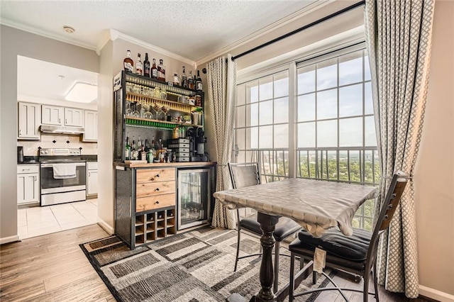 bar featuring ornamental molding, beverage cooler, under cabinet range hood, electric stove, and a dry bar