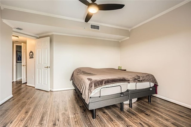 bedroom featuring baseboards, ornamental molding, wood finished floors, and visible vents