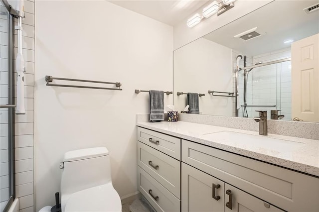 full bath with vanity, a shower with door, toilet, and visible vents