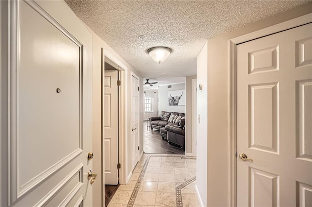 hallway featuring baseboards and a textured ceiling