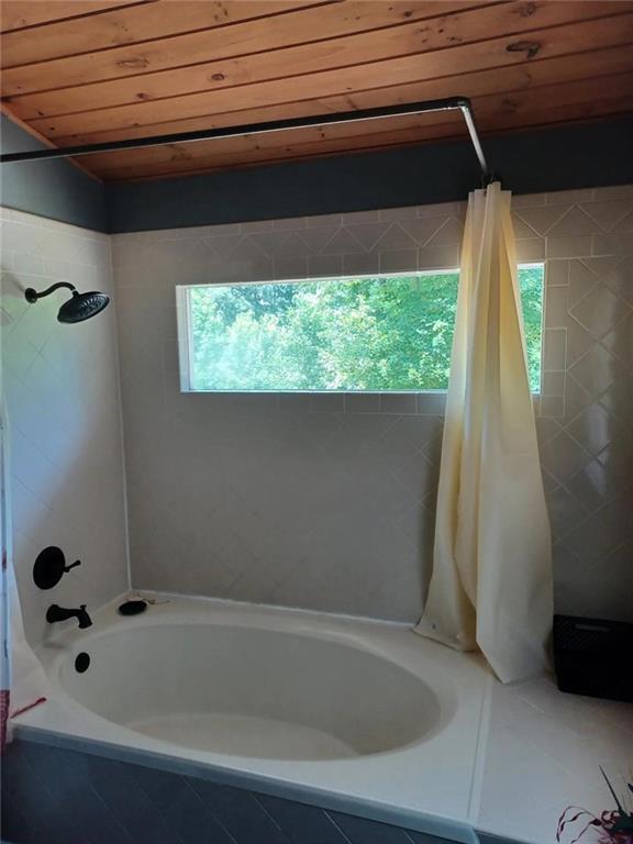 bathroom featuring wood ceiling and tiled shower / bath