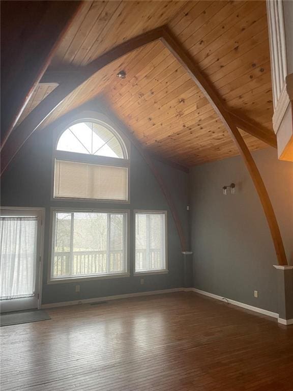 unfurnished living room with high vaulted ceiling, wood ceiling, baseboards, and wood finished floors