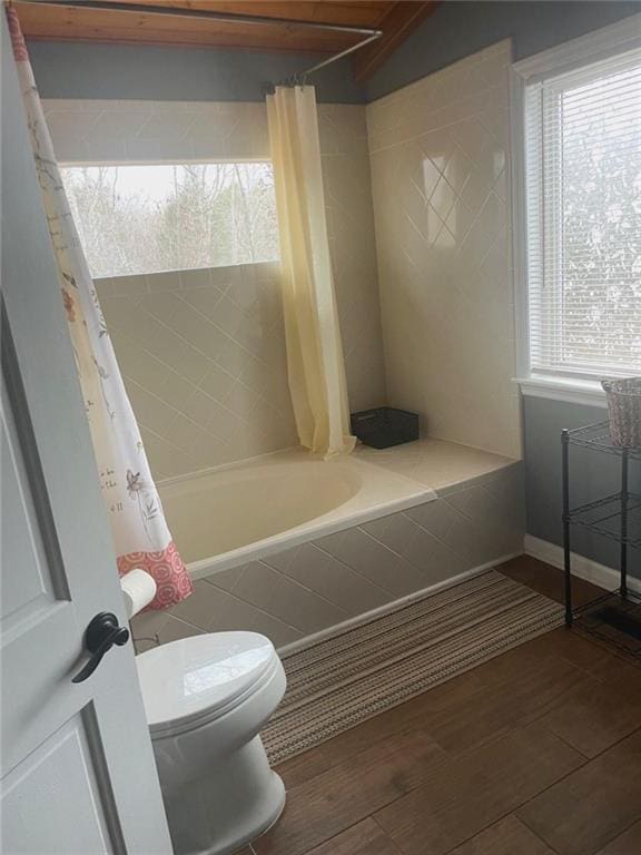 bathroom with toilet, baseboards, tiled shower / bath, and wood finished floors