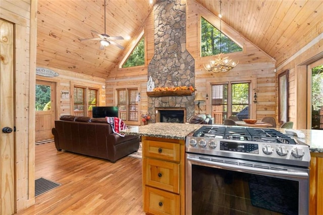 kitchen with high vaulted ceiling, stainless steel gas stove, wooden walls, and light hardwood / wood-style flooring