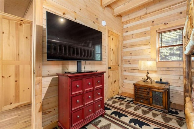 interior space featuring wood walls, light hardwood / wood-style floors, and beam ceiling