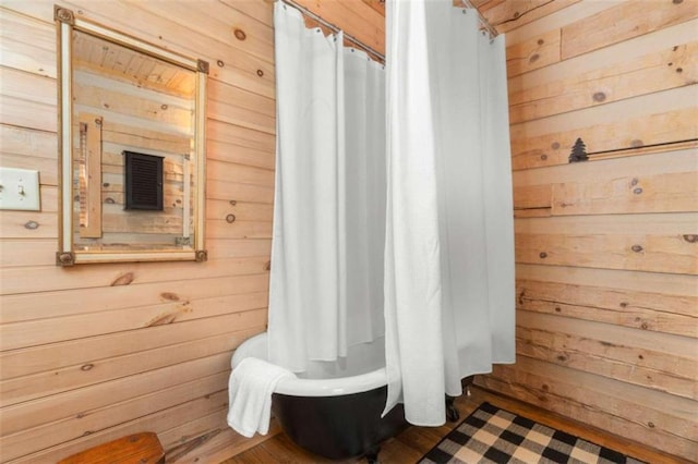 interior space featuring a shower with shower curtain and wooden walls