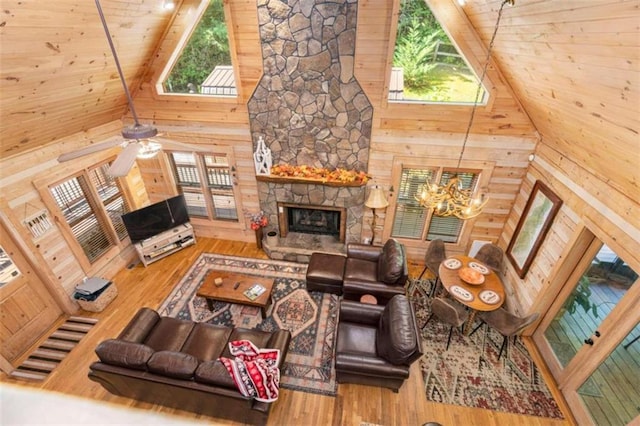 living room featuring high vaulted ceiling, wood-type flooring, wood walls, and a healthy amount of sunlight