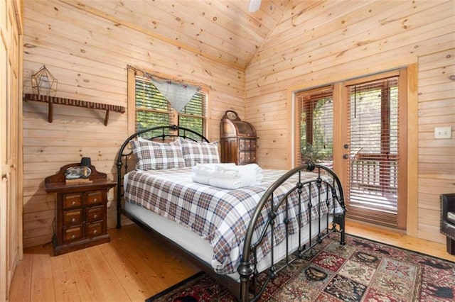 bedroom with hardwood / wood-style floors, wooden walls, and vaulted ceiling