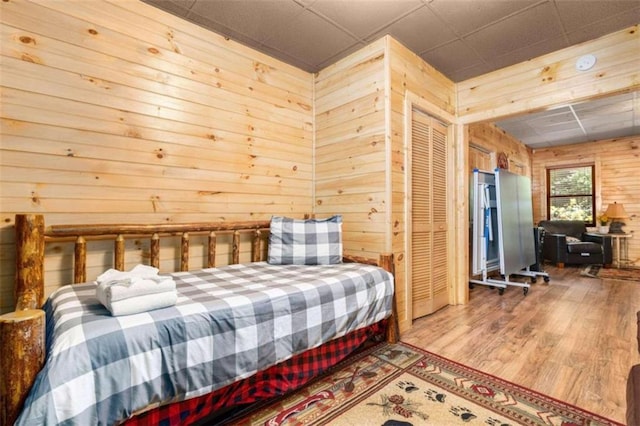 bedroom featuring a closet, wooden walls, and light hardwood / wood-style floors