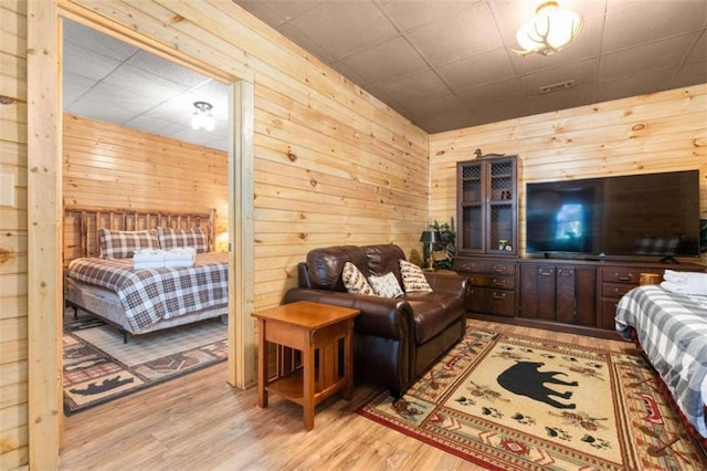 bedroom with light wood-type flooring and wooden walls