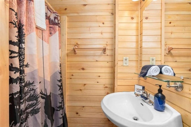 bathroom featuring sink and wooden walls