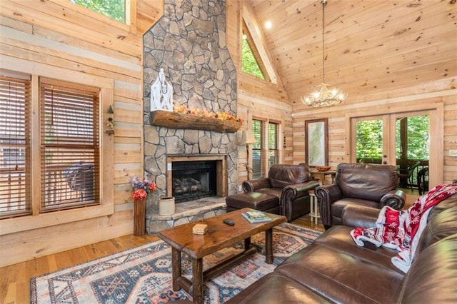 living room featuring high vaulted ceiling, hardwood / wood-style flooring, wooden walls, and a stone fireplace