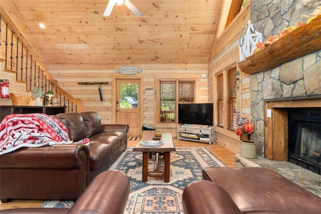 living room with a fireplace, wood-type flooring, wood walls, and ceiling fan