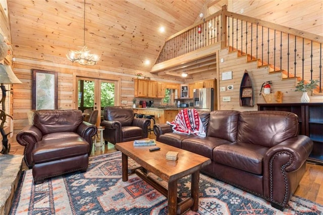 living room with wood walls, an inviting chandelier, french doors, light hardwood / wood-style floors, and high vaulted ceiling