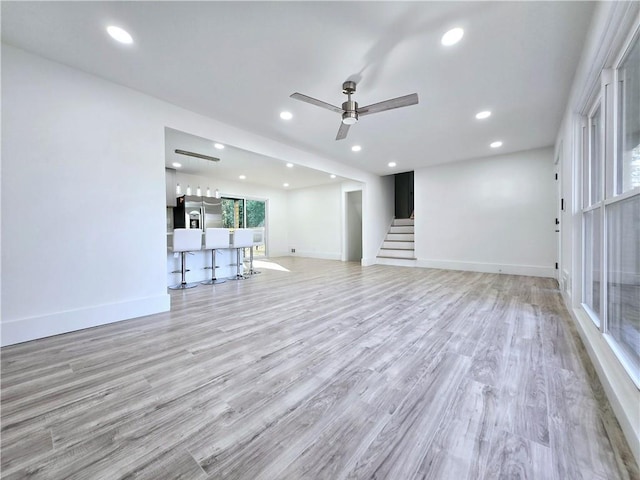 unfurnished living room featuring stairs, recessed lighting, and baseboards