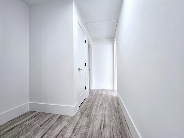 corridor featuring baseboards and wood finished floors