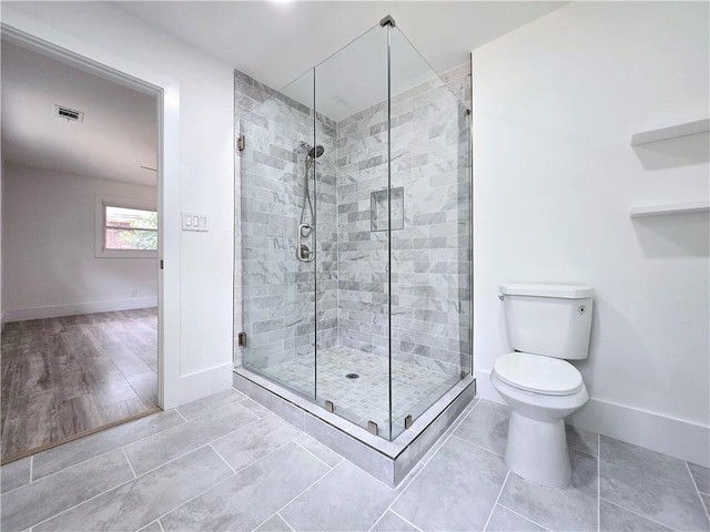 bathroom with toilet, visible vents, a stall shower, and baseboards