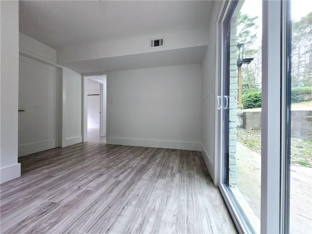 unfurnished room with light wood-style floors, visible vents, and baseboards