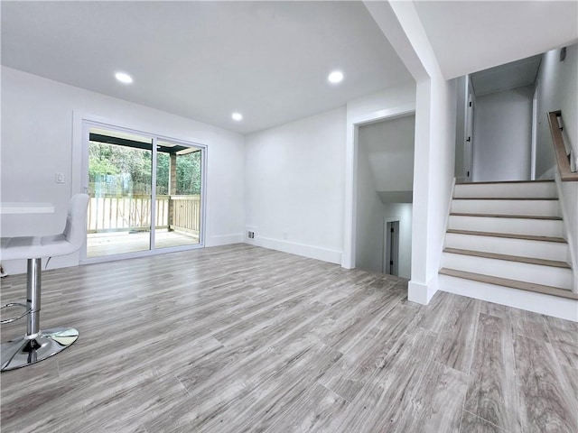 unfurnished living room with visible vents, baseboards, stairway, recessed lighting, and wood finished floors