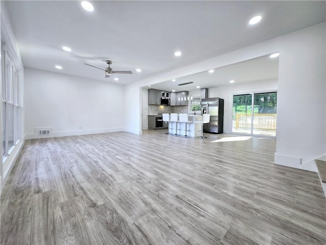 unfurnished living room with visible vents, recessed lighting, light wood-type flooring, and baseboards