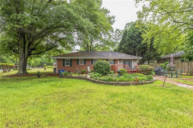 view of front of property with brick siding, a front lawn, fence, and a wooden deck