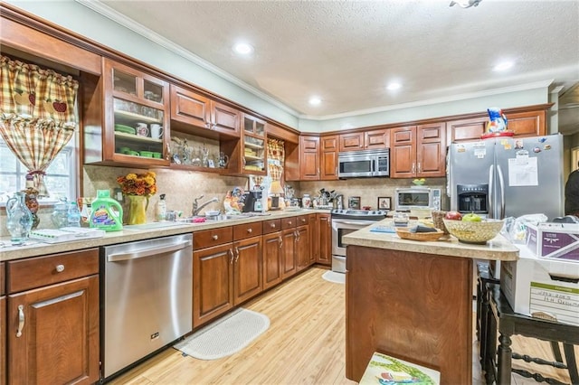 kitchen with crown molding, light countertops, stainless steel appliances, decorative backsplash, and light wood-type flooring