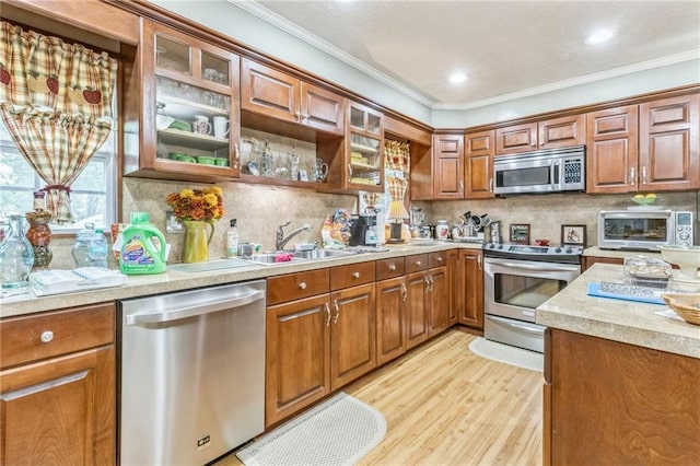 kitchen with crown molding, stainless steel appliances, brown cabinets, and a sink