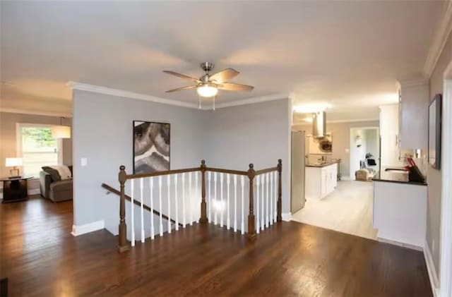 hallway with ornamental molding, wood finished floors, an upstairs landing, and baseboards