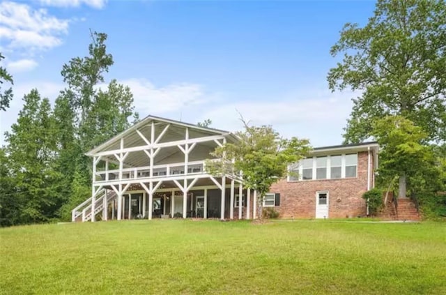 rear view of house with a yard, brick siding, and stairway