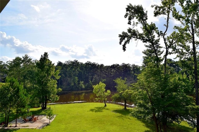 view of community with a lawn, a water view, and a view of trees