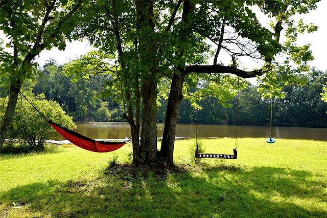 view of community with a yard, a forest view, and a water view