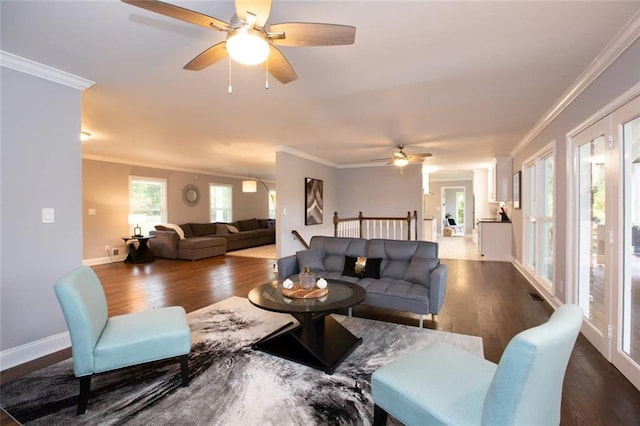 living area featuring dark wood finished floors, visible vents, ornamental molding, a ceiling fan, and baseboards