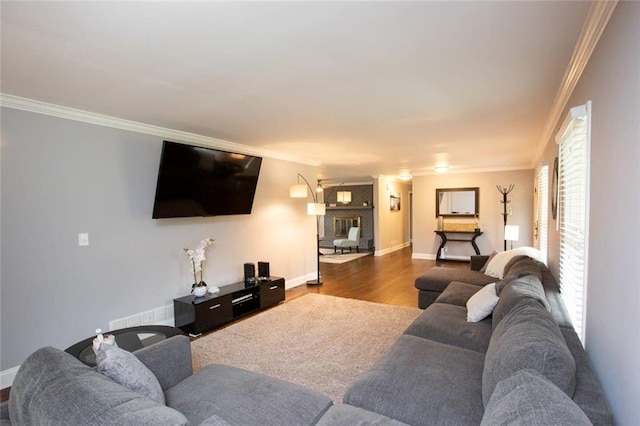 living area featuring ornamental molding, a brick fireplace, wood finished floors, and baseboards